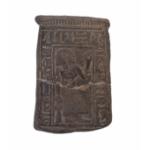 The front of a ceramic stele with a figure crouched in adoration, surrounded by an inscription of hieroglyphics.   