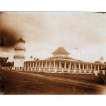 A photo of a building with a two-tiered roof with corners curling up. There are white pillars around the porch of the building and a white tower with two decks on it to the left. 