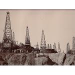 Oil field in Myanmar with many derricks, and local labourers scattered around the scene.