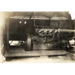 Engine inside a National Rig, with a large bull wheel on the left, and pipes running off to the right. 