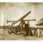 A photo of a star drilling machine with a tractor in front. There are five men standing on the right-hand of the photo and there are trees in the background.