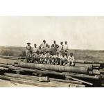 Un groupe d’hommes debout et assis sur une pile de tubage. Le groupe est un mélange de foreurs internationaux et d’ouvriers. 