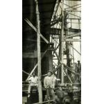 An International Driller and two local workers standing underneath an oil rig.