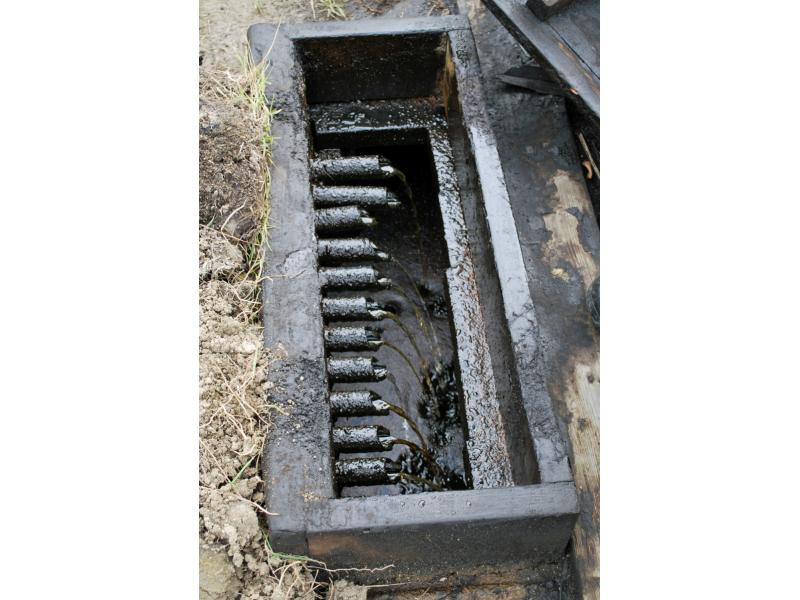 Eleven spouts inside a black box pour a mixture of water and oil into a separating tank.