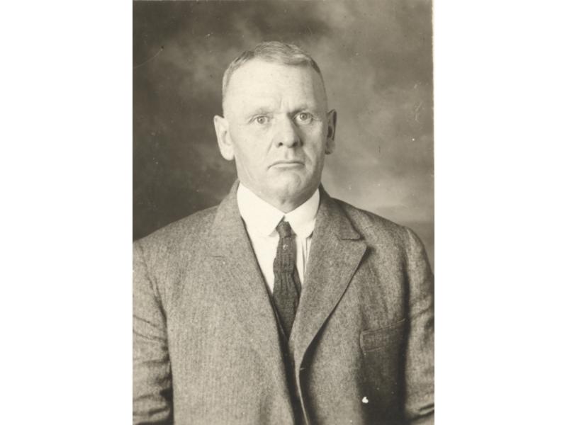 A photo of an older man wearing a jacket and tie.