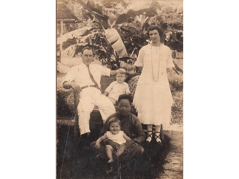 Family portrait of James Sr and James Jr, sitting on a bench with Ada standing and Edward sitting on the lap of a Sumatra servant. 