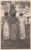 Front of a postcard showing the backs of three women in traditional dress.