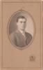 A portrait of Charles Holmes. He is clean-shaven and wearing a suit and tie. The photo is set into a light brown frame with a crest of a lion at the bottom and the inscription "G.B. Robson. Petrolia, Ont."