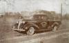 A two-door truck parked on the side of a dirt road with a field and trees in behind it. The truck is dark and has "Stover and Rawlings. Oil & Gas Well Contractors. Chatham" written on the door. 