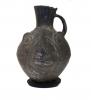 Front view of black stirrup-handle jug, shaped like a llama's head. 