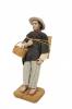 Painted clay figurine of a man in a straw hat, carrying a basket.