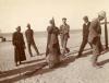 A photo of an Egyptian man holding the tail of a fish that is as tall as himself. Five other men stand around him. 