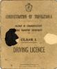 La page couverture d’un permis de conduire. Il est brun pâle et il y a une tache noire sur le côté gauche et une tache décolorée sur le côté droit. Il y a un écusson dans la partie supérieure. Le document indique : « Administration Tripolitaine. Nazirat du Département des Communications du Transport Routier. Permis de conduire de classe 1. »