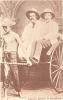 William McRae and William McEwen being pulled in a rickshaw by a local boy. They are wearing white suits and pith helmets.