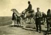 An International Driller on a camel, with another posing on the ground. There are a number of local men with them.