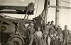 A photo of eleven men in front of a drilling machine with the words "Walker Neer" on it. They are wearing work clothes.