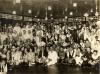 A photo of a large group of people dressed up in costumes. They are in a large room with wooden floors and paper lanterns hanging from the ceiling.