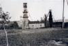 A photo showing eight oil rigs in a Polish oil field. The rigs are covered in wood. There are hills in behind the rigs. 