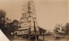 A photo of a covered oil rig set on stilts. There are trees in the background. 