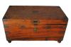 A smooth wooden chest with a reddish hue. There are pieces of brass on the corners. The lock is also made of brass.