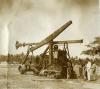 A photo of a star drilling machine with a tractor in front. There are five men standing on the right-hand of the photo and there are trees in the background.