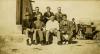 Seven International Drillers sitting on a stone ledge. There are two people in the background with a car.